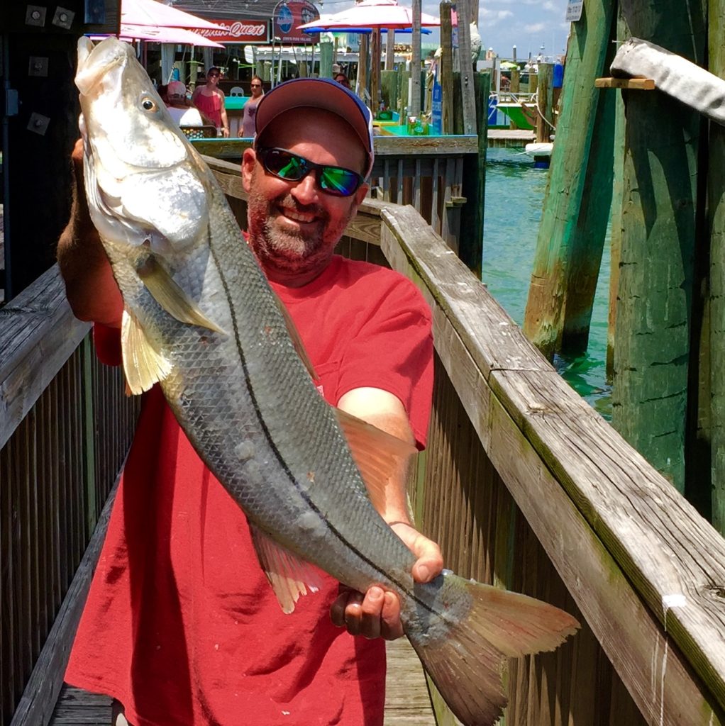 Jacob 'Smokey' Grant showing off a monster snook he caught while handling a pigfish under the dock at Hubbard's Marina