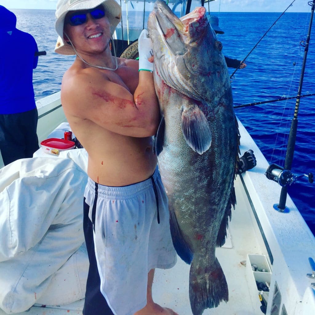 Huy Nguyen showing off his 65lb true black grouper from his Flying HUB 1 private charter at Hubbard's Marina